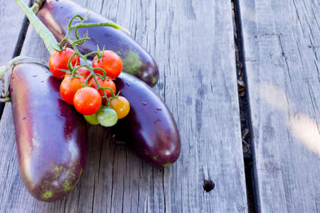 Vintage blue eggplant and cherry tomatoes on a wooden backgroundの写真素材