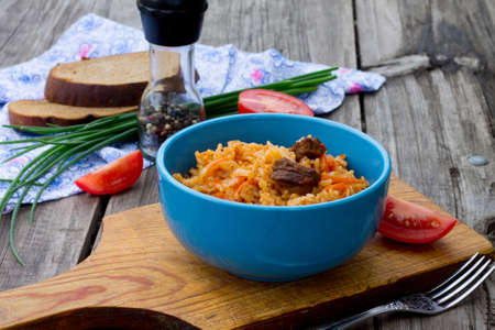 Pilaf with meat and tomatoes on a wooden backgroundの写真素材