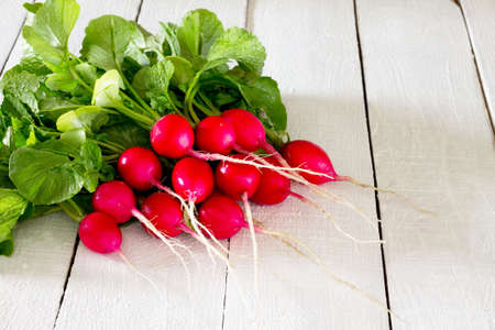 A bunch of radishes on a white wooden tableの写真素材