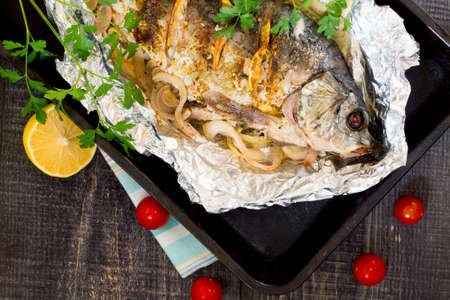 Baked fish (carp) with onion and lemon in a rustic styleの写真素材