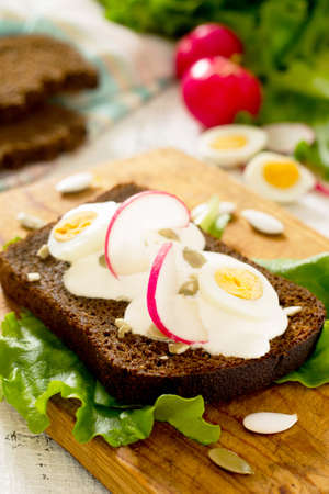Toast sandwich with egg, radish, pumpkin seeds and sour cream, selective focus.