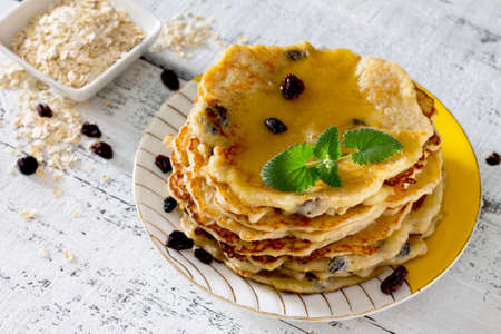 Oatmeal Pancakes with honey and raisins on a rustic table