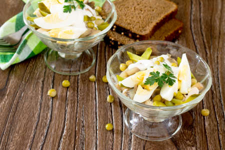 Salad with chicken and green peas on a wooden table, rustic style.