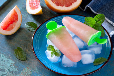 Delicious fruit ice with grapefruit on vintage wooden background.