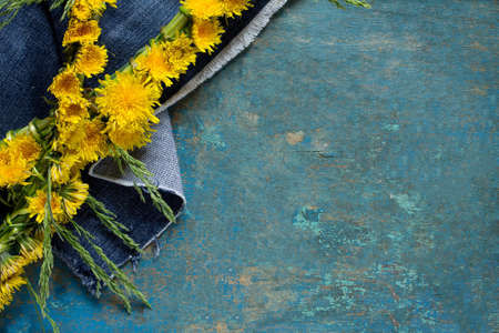 Yellow dandelions (braided wreath) on vintage blue background, place for your text.の写真素材