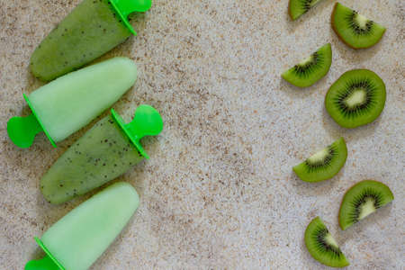 Ice cream with kiwi on brown stone background, place for your text. View from above.の写真素材