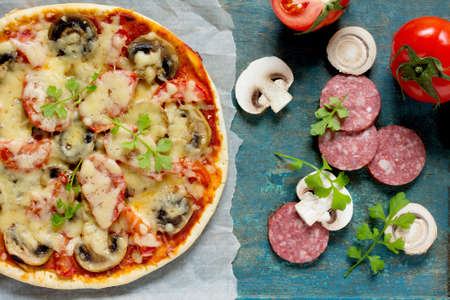 Tasty Italian pizza with pepperoni, tomatoes, cheese and mushrooms served vintage wooden table background.の写真素材
