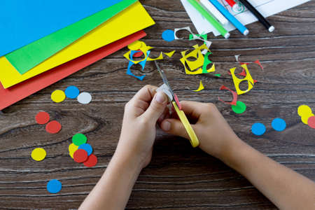 The child holds a cardboard circle in the hands of a caterpillar and adds the appropriate number...