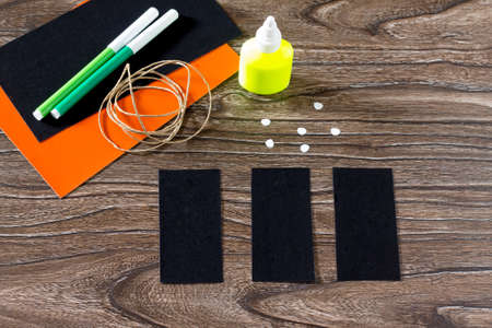 The child create a greeting card Halloween black cat out of paper. Glue, scissors, leaves velvet...