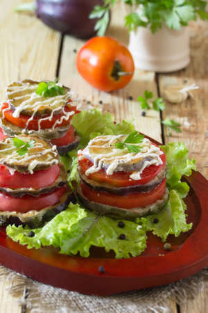 Fried eggplant a stack of folded with tomato, garlic and cream sauce on salad leaves.の写真素材