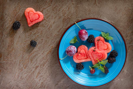 Slice of watermelon heart and berry fruit on brown stone background, copy space. Top view .の写真素材