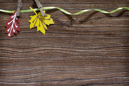 Autumn colored paper leaves on a wooden board, copy space. A sheet of paper craft for children....