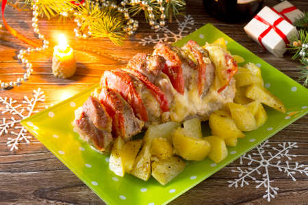 Baked meat with cheese and tomato with baked potato on a festive Christmas table.の写真素材