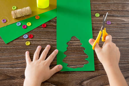 The child create Christmas greeting cards paper festive fir. The child cut out paper details. Children's Art Project, needlework, crafts for children.の写真素材