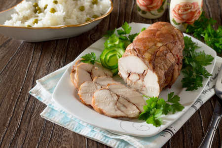Roll of chicken, baked meat with red wine and rice with green peas on a wooden table.の写真素材
