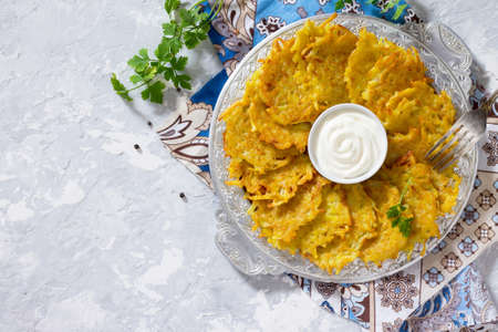 Homemade traditional potato pancakes, served with sour cream sauce, top view. Hanukkah holiday meal on vintage concrete background. Copy space.の写真素材