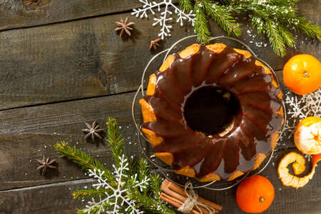 Christmas frame. Traditional homemade cupcake with chocolate icing. Dessert new year decorations tangerines on vintage wooden background. Top view.の写真素材