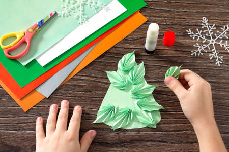 The child makes a paper Christmas tree, snow, fox and hare. Creating paper detail Christmas tree. Children's art project, a craft for children.の写真素材