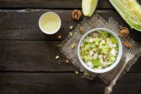 Salad with cabbage, chicken, apple, cucumber and walnuts. Healthy food concept. Top view.の写真素材