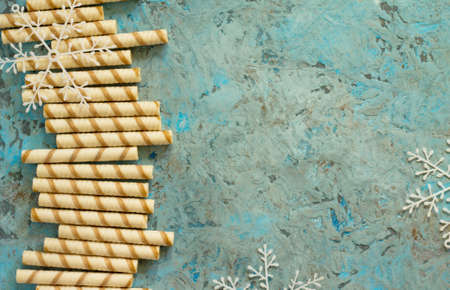 Christmas frame. Tubules waffles with cream and chocolate on a gray stone background. Copy space. Top view.の写真素材