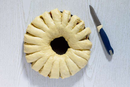 Preparation of traditional Easter kulich meal: raw dough wrapped in roll filled baking on a wooden table.の写真素材