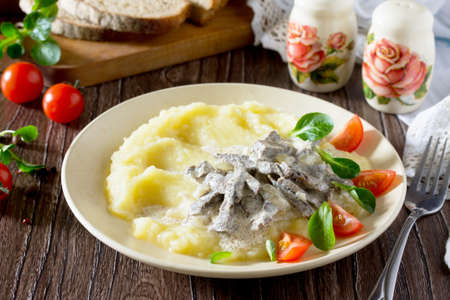 Traditional hot meat stew with sour cream and garnish mashed potatoes on a wooden table. Concept of healthy food.の写真素材