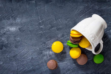 Mugs Macaron cakes on black stone background, top view. The cozy breakfast. Copy space.の写真素材