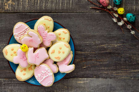 Easter background. Easter cookies on a plate and twigs of willow on a wooden table. Easter recipe.の写真素材