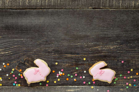 Easter frame. Easter Bunny Cookies and confectionery sugar sprinkling on a wooden table. Easter...