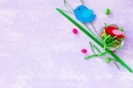 Creating children's Easter table. Paper quilling, paper nest, bird, painted eggs and sweets on the...