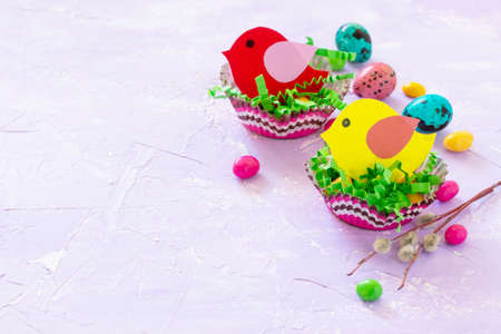 Easter decorations children's table. Easter table decoration nest with baby bird paper and candy, painted quail eggs. Copy space.の写真素材