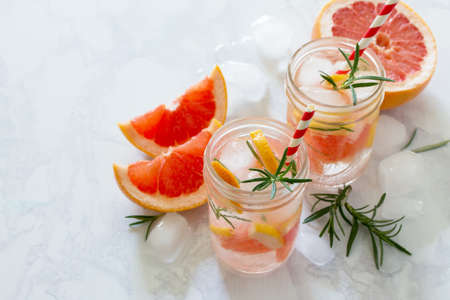 Refreshing summer drink with grapefruit and rosemary on a stone background. The concept of healthy and dietary nutrition. Copy space.の写真素材