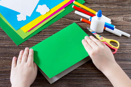 The child folds the pieces of paper. Greeting card with flowers on Mother's Day. Children's art project, craft for children. Handmade. Craft for children.の写真素材