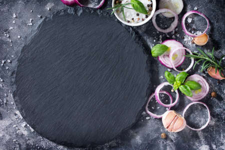 Black background of cooking with onions, garlic, fresh herbs and spices, top view. Copy space.の写真素材