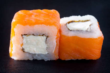 Roll Cheese salmon is isolated on a black slate board - salmon, soft cheese, nori, rice.の写真素材