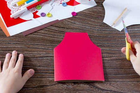A child carves paper details of a gift from a paper apron postcard on mother's day. Hand-made. The project of children's creativity, needlework, crafts for children.の写真素材