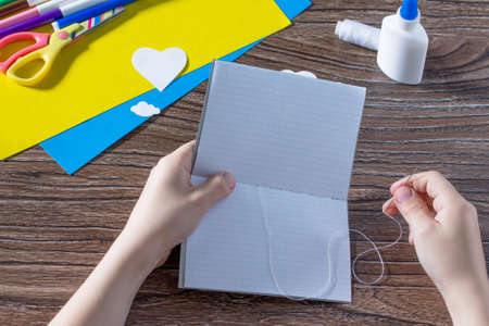 The child sews details. The child creates a note pad handmade applique decorated balloon, craft paper. The project of children's creativity, needlework, crafts for children.の写真素材