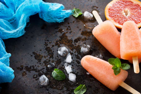 Delicious fruit ice grapefruit and ice on a stone background. Place for the text.