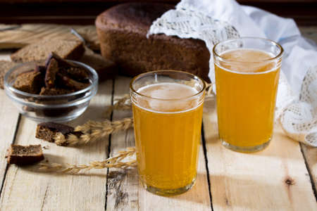 Traditional Russian cold rye drink Kvas in a glass and a jug on a wooden table. Kvass from bread, rye malt, sugar and water.の写真素材