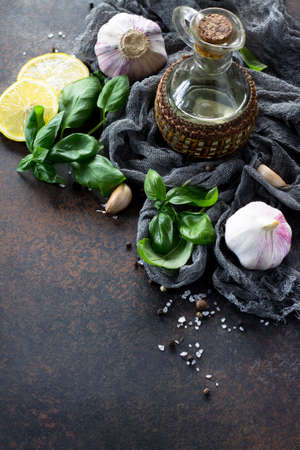 Ingredients for cooking - garlic, lemon, basil, spices and olive oil. Food background on the kitchen table. Copy space.の写真素材