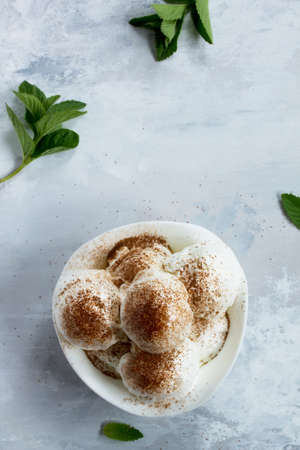 Balls of cream ice cream with chocolate, mint and coffee in a cup on a marble kitchen table. Top...