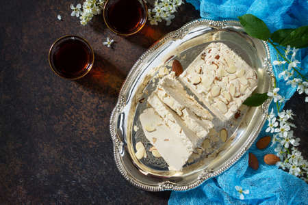 Halva with almond petals and tea on the kitchen table. Turkish and Arabic sweets. Eating Ramadan....