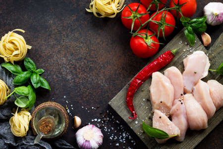 Fresh meat. Preparation of Italian cuisine pasta with chicken fillet, various spices and tomatoes. Top view with copy space. Food background.の写真素材
