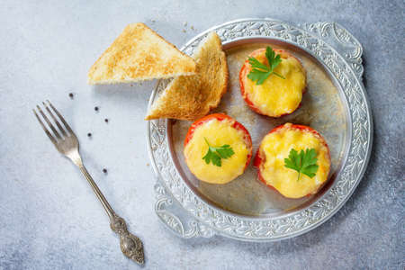 Stuffed tomatoes. Tomatoes baked with cheese and chicken, served with croutons of white bread. Top view.の写真素材