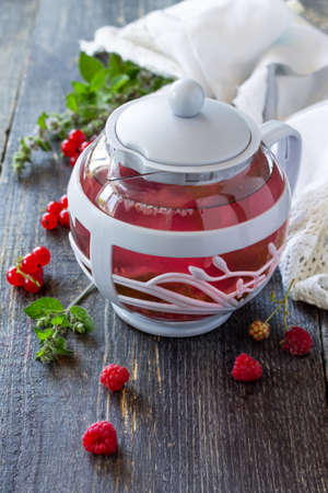Fruit berry tea with mint, red currant and raspberries on a wooden kitchen table.の写真素材