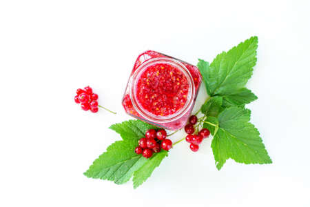 Homemade jam. Glass jar with red currant jam on white background. Preserved berry.の写真素材