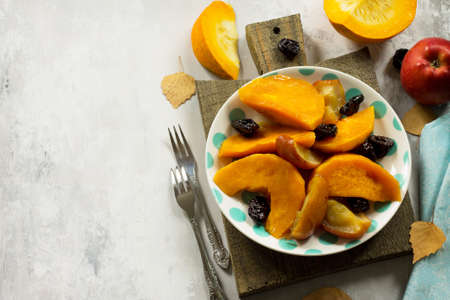 Pumpkin baked with apples, prunes and spices in a bowl on a stone background. Flat flay, top view with copy space.の写真素材