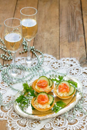 Christmas snack on the festive table. Tartlets with salad, decoration from salmon and cucumber.の写真素材