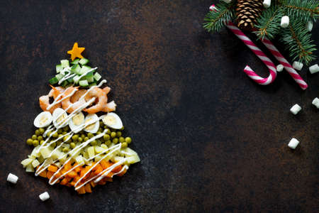 Christmas tree from a salad olivier on a brown rusty stone or metal background.  Beautiful Christmas and New Year background for food top view of a blank space for text.の写真素材