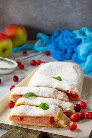 Homemade apple strudel with fresh apples, cranberry and sugar powder on slate or stone background. Copy space.の写真素材
